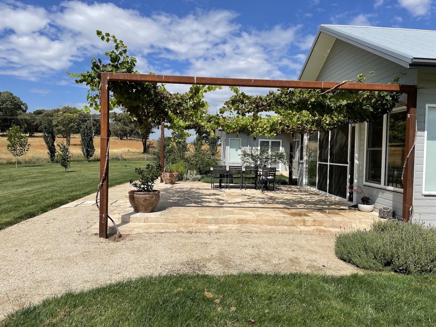 A timber pergola and established garden beside a mown lawn