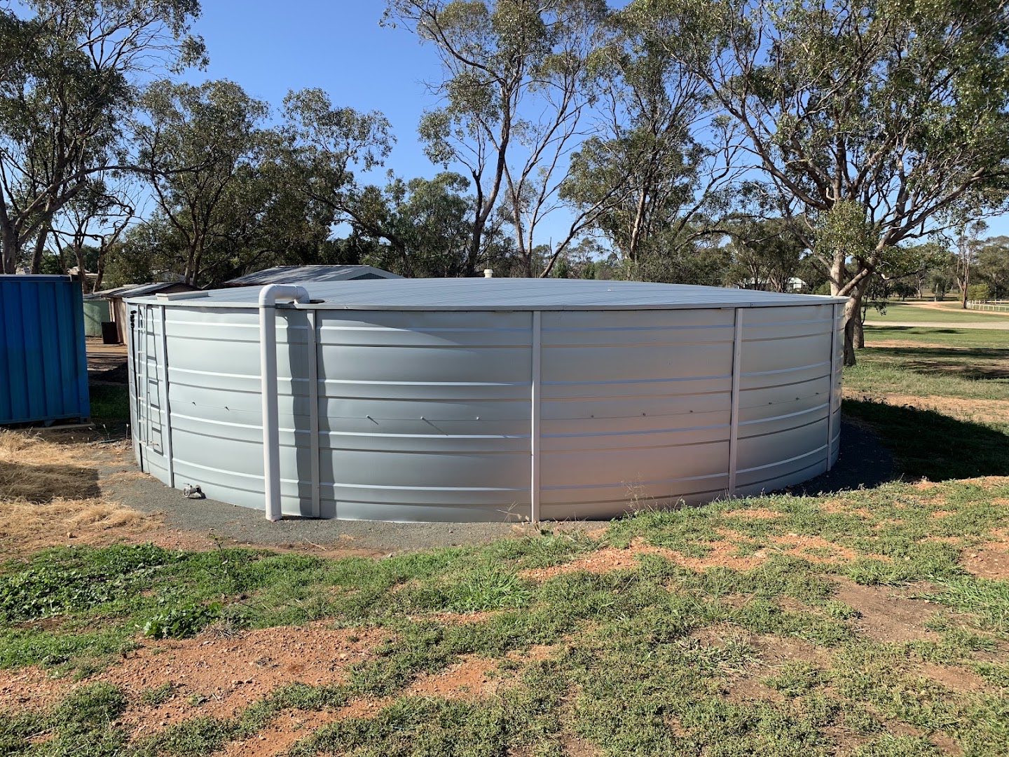 A large corrugated steel water tank standing among gum trees