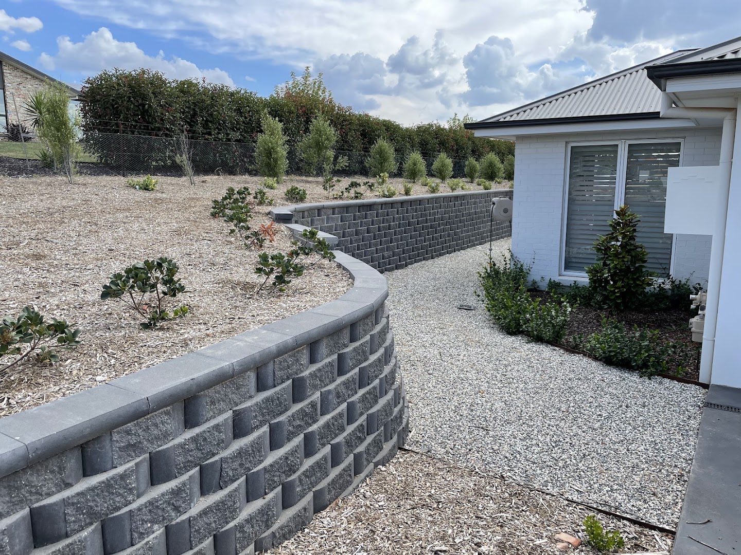 A rendered block retaining wall and garden bed beside a new home