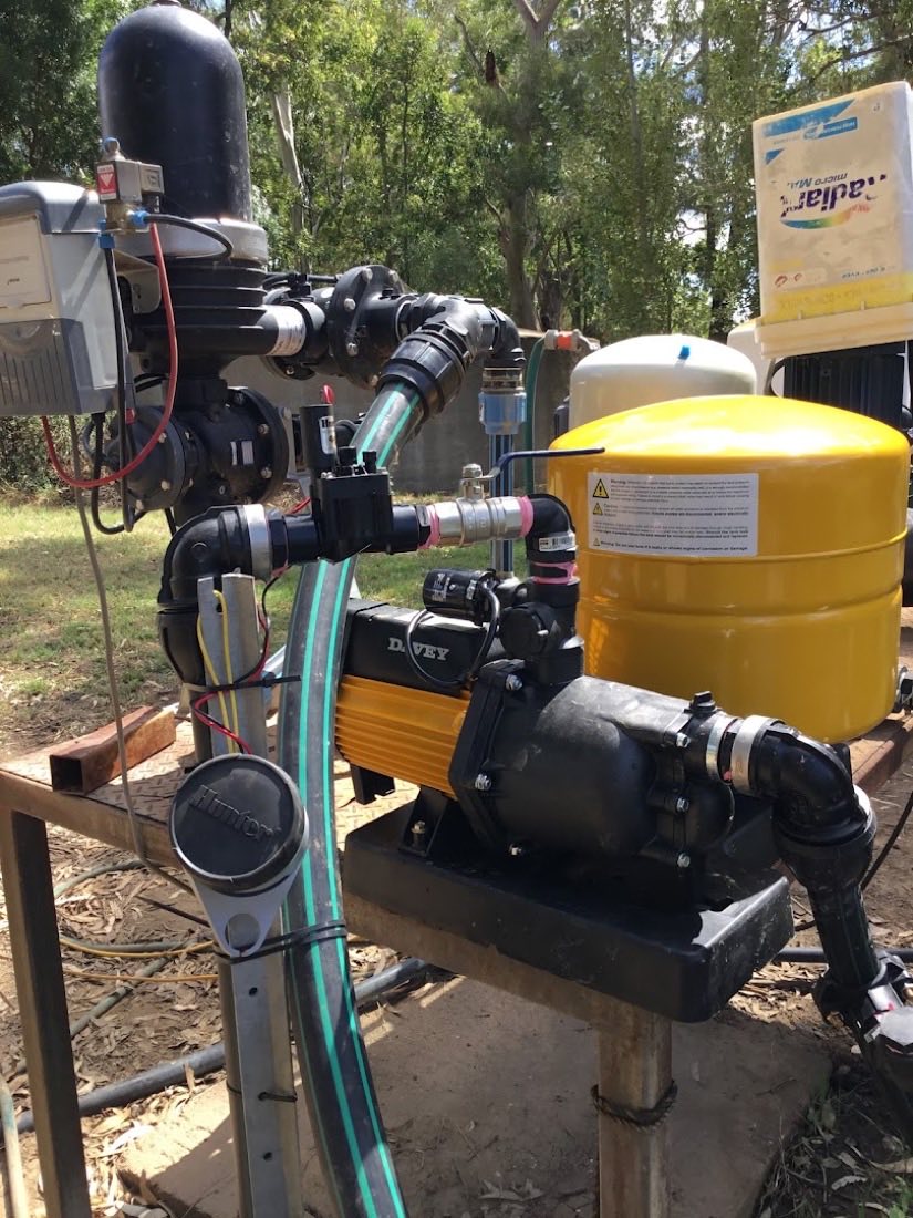 A pump, filter and yellow pressure tank mounted on a frame beside a tank