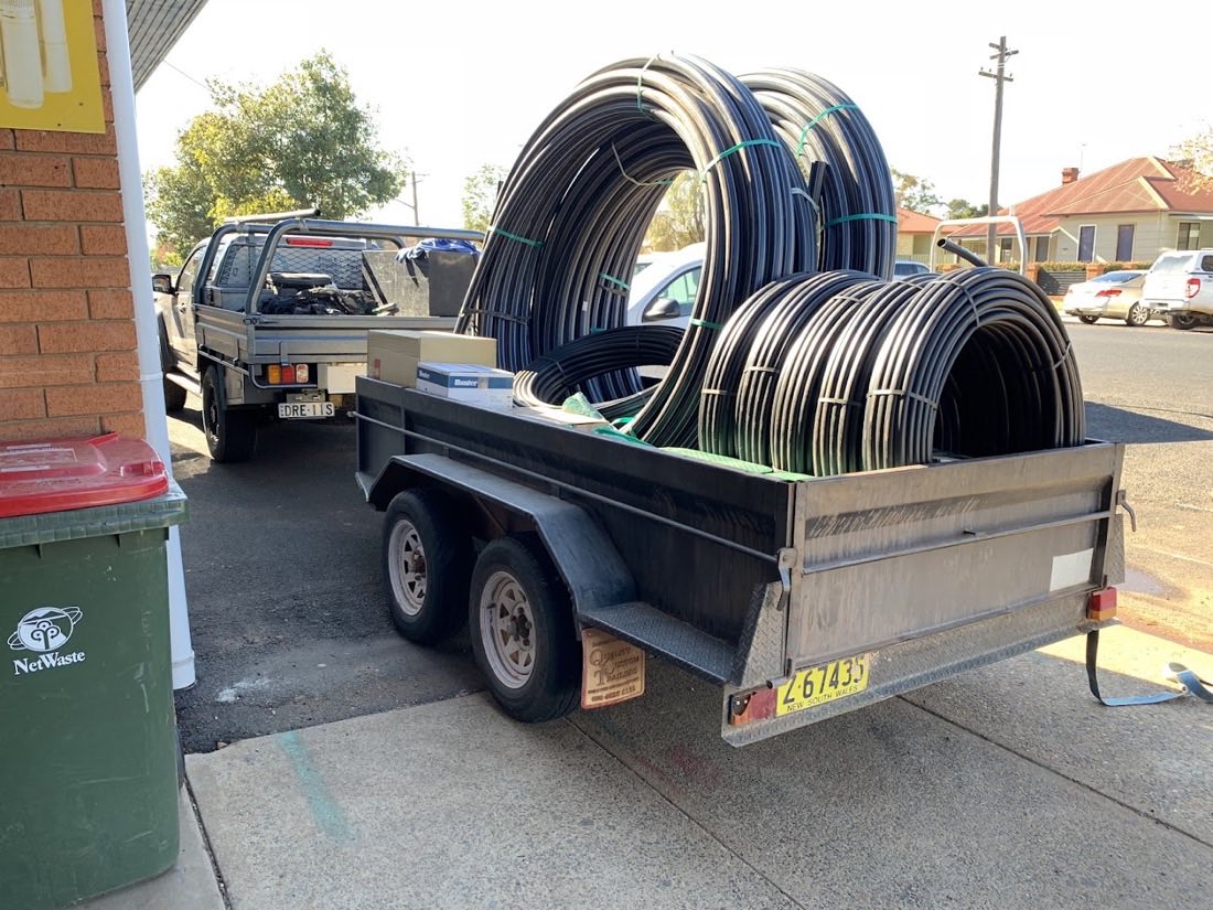 A trailer loaded with coils of black poly pipe