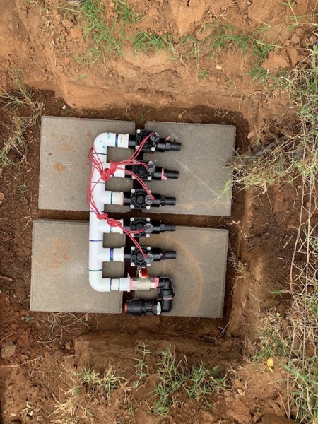 A bank of irrigation valves set in a concrete box below ground level