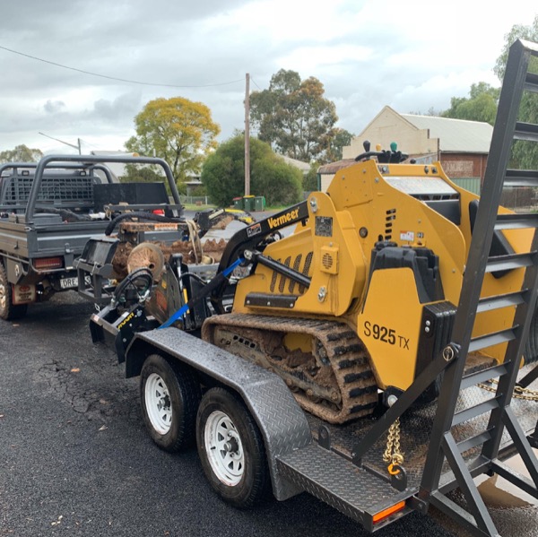 A ute and trailer loaded with a tracked mini loader