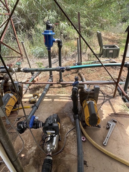 Valves and pipework installed under a shed roof beside a steel tank
