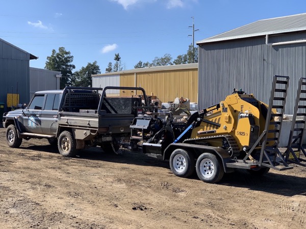 A ute and trailer with a tracked mini loader parked at a yard